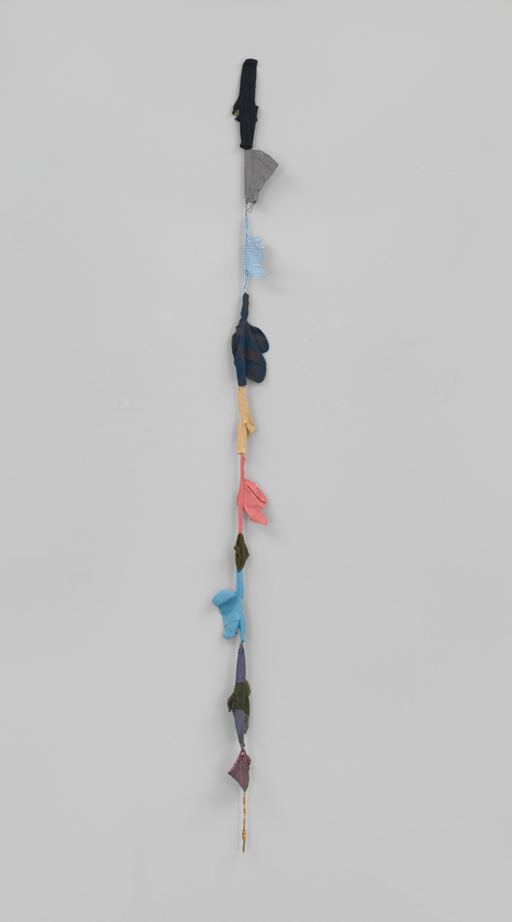 A vertical string of colorful, knotted fabrics against a white background.