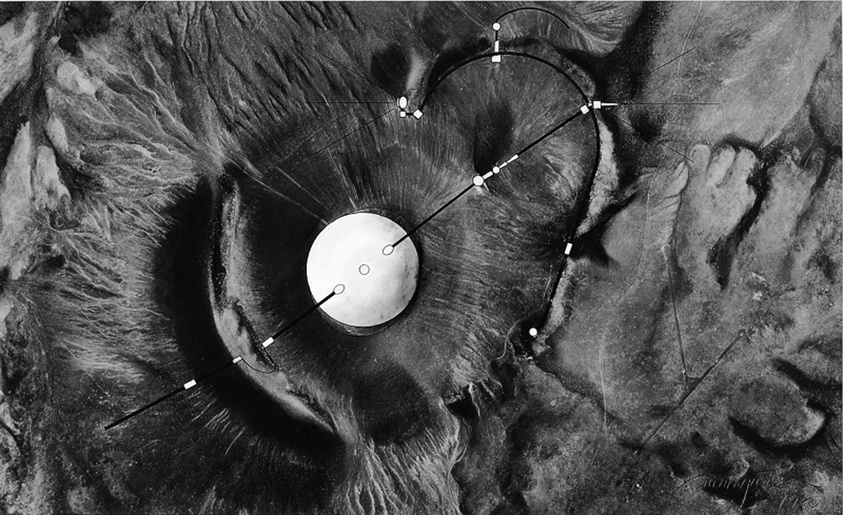 A large circular structure sits in the center of a barren landscape, intersected by straight and curved lines.