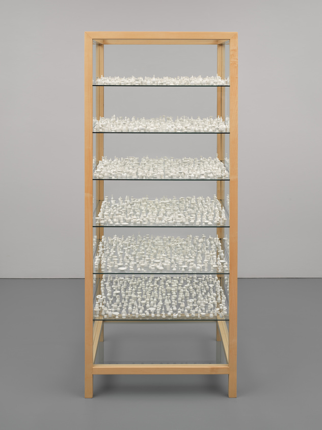 A wooden bookshelf with five shelves filled with numerous small white figurines against a gray background.