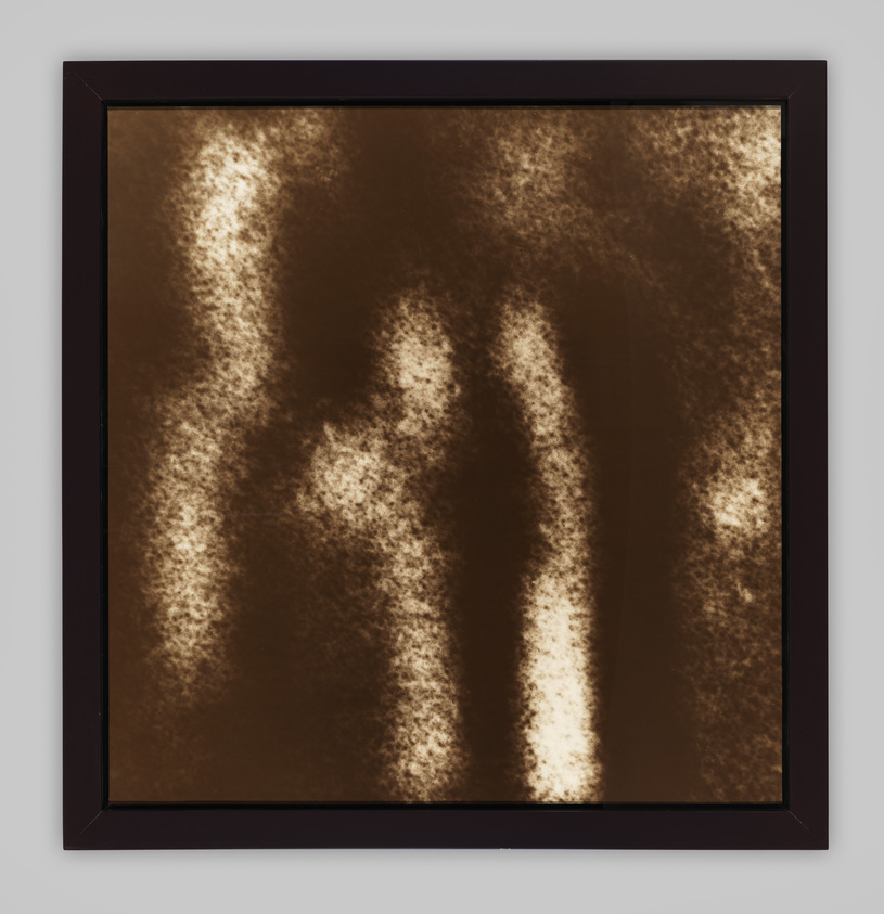 A framed abstract artwork featuring diffuse, light-colored vertical streaks against a dark brown background, creating a soft, glowing effect.