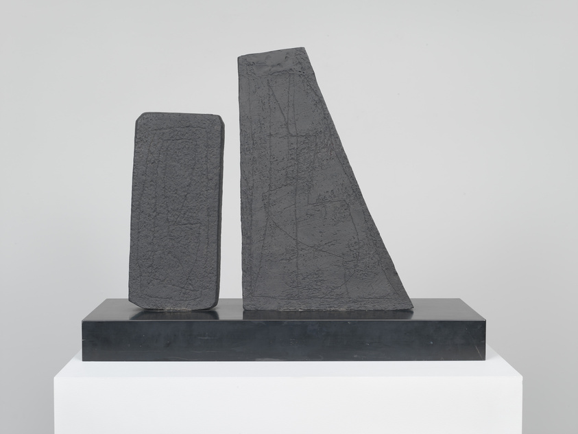 Two abstract, textured stone sculptures on a black base, one rectangular and one triangular.