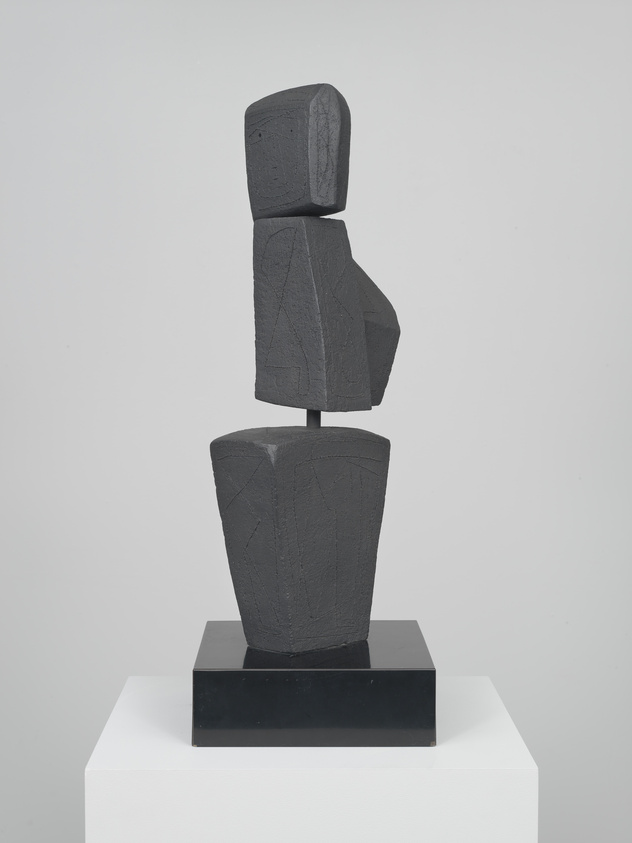 Abstract black sculpture with geometric shapes stacked vertically on a pedestal.