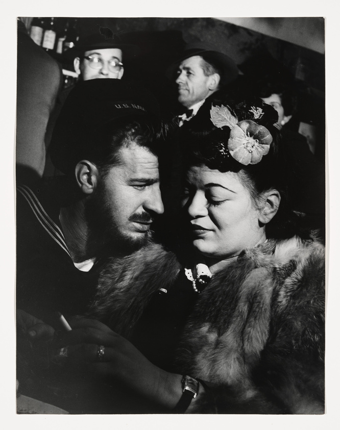 Vintage photo of a sailor and a woman in conversation, surrounded by onlookers.