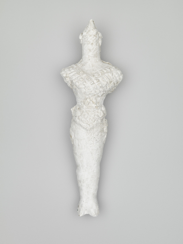 A white textured sculpture of a stylized female figure with a defined waist and broad shoulders against a grey background. The figure has no distinct facial features and is presented in a frontal view.