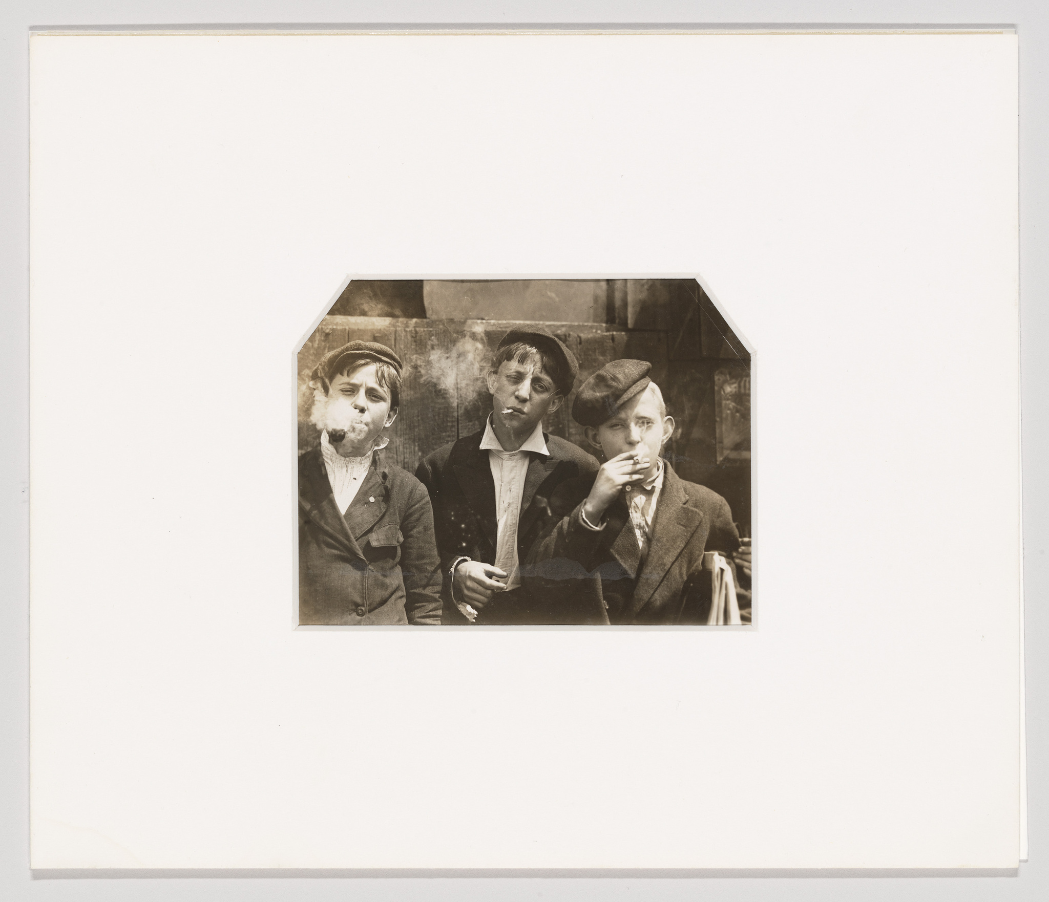 Vintage photo of three young men in suits, two blowing smoke rings and one eating, with a whimsical expression.