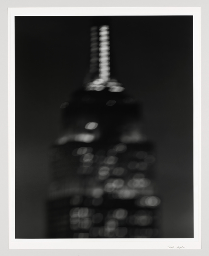 Blurred black and white photo of a city skyscraper at night, framed and signed.