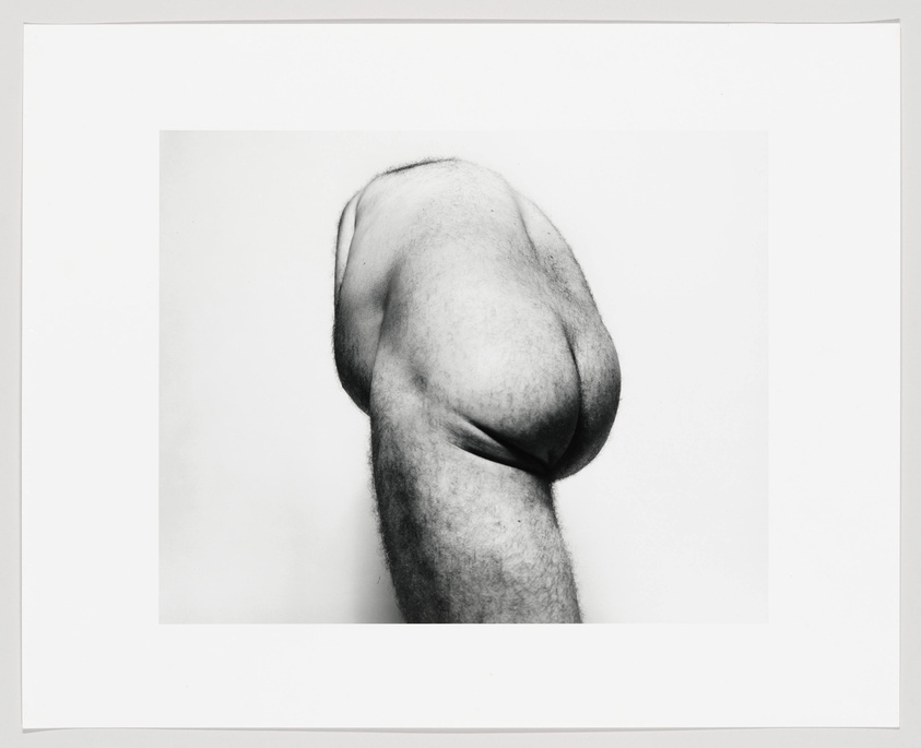 A white man's upper body is contorted, revealing his butt