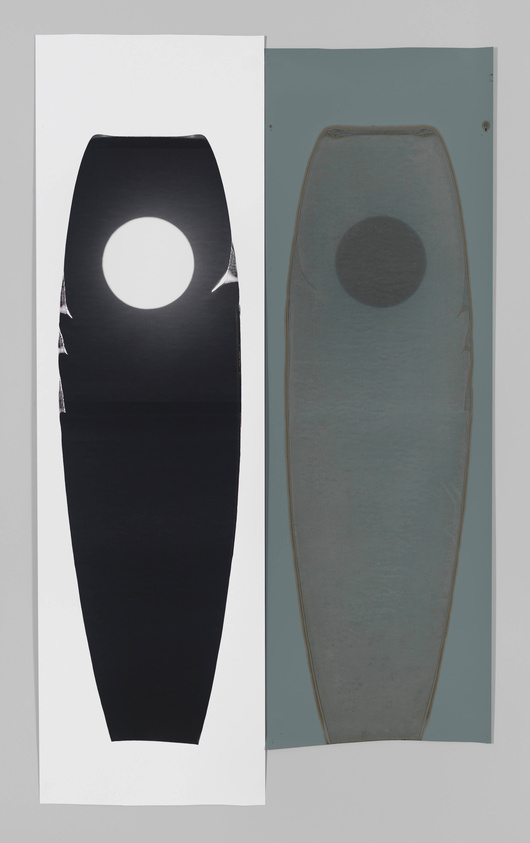 A photograph of two vertical panels placed side by side. The left panel features a graphic silhouette of a surfboard with a circular cutout near the top, set against a white background. The right panel shows an actual surfboard mounted on a wall, with a similar circular shape visible through a semi-transparent material, mirroring the design of the graphic silhouette.