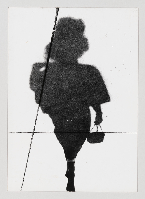 A high-contrast black and white image of a person's shadow on a textured surface, bisected by a diagonal line, with the shadow showing a silhouette of an individual seemingly in motion, carrying a bag.