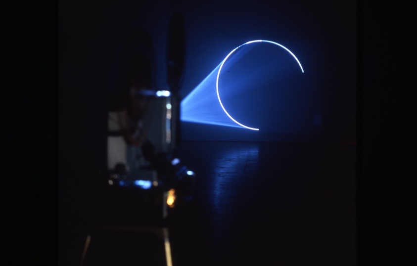 A projector casting a blue crescent moon and light beam on a dark wall.