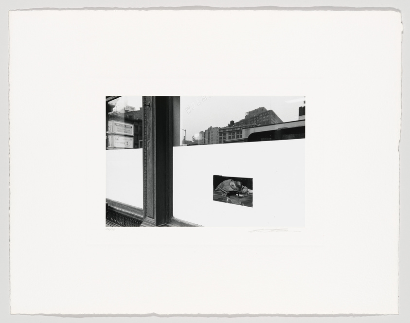 A black and white photograph featuring a collage of images. On the left, a window frame reveals a blurred cityscape with buildings and a sign that reads "WORK." On the right, a smaller, clear image of a man working on a boat is inset against a white background. The overall composition is bordered by the rough edges of the photo paper, and there are artist's signatures at the bottom.