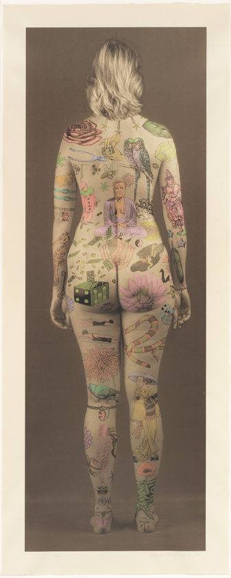 A person stands with their back to the viewer, displaying a full body suit of colorful tattoos featuring a variety of images including flowers, animals, and cultural symbols. The tattoos cover the entire visible skin, creating a vibrant tapestry of art on the body.