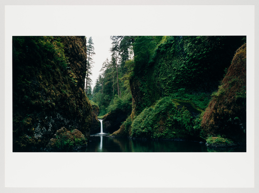 A serene landscape featuring a small waterfall nestled between lush, moss-covered cliffs with a calm river in the foreground, surrounded by a dense forest under an overcast sky.