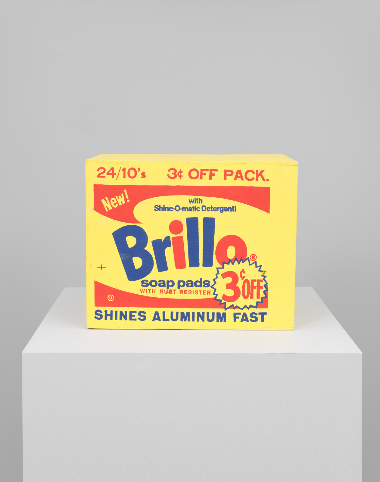 Yellow Brillo soap pads box with red and blue text, offering 3¢ off. Promises to shine aluminum fast. Placed on a white pedestal.