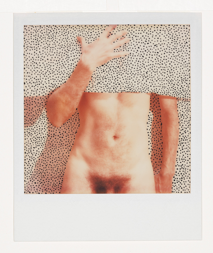 A person stands against a dotted background, with their upper body obscured by a matching dotted cloth, and their hand raised to cover their face.