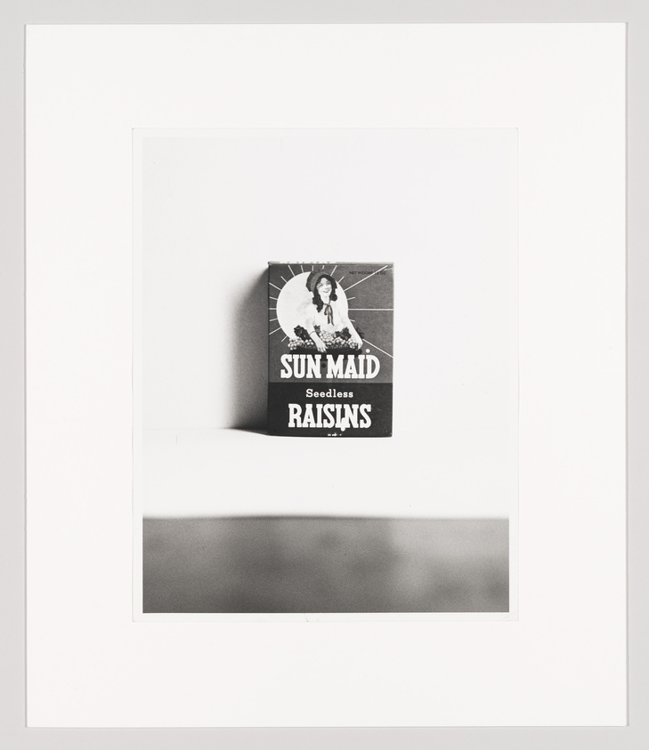 A black and white photograph of a Sun-Maid Seedless Raisins box centered on a white background with a shadow cast below it.