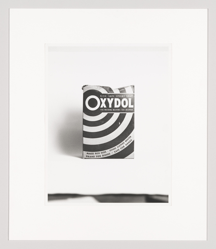 A black and white photograph of a vintage Oxydol soap powder box with bold stripes and text, centered and framed with a wide white border.