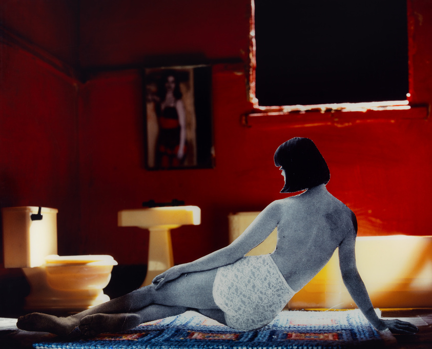 A silhouette of a woman sitting in a red room with a poster on the wall and sunlight streaming through an open window.