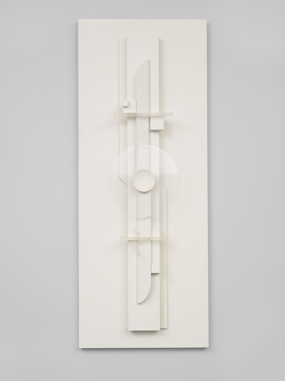 A vertical, monochromatic white relief sculpture with geometric and abstract shapes mounted on a wall.
