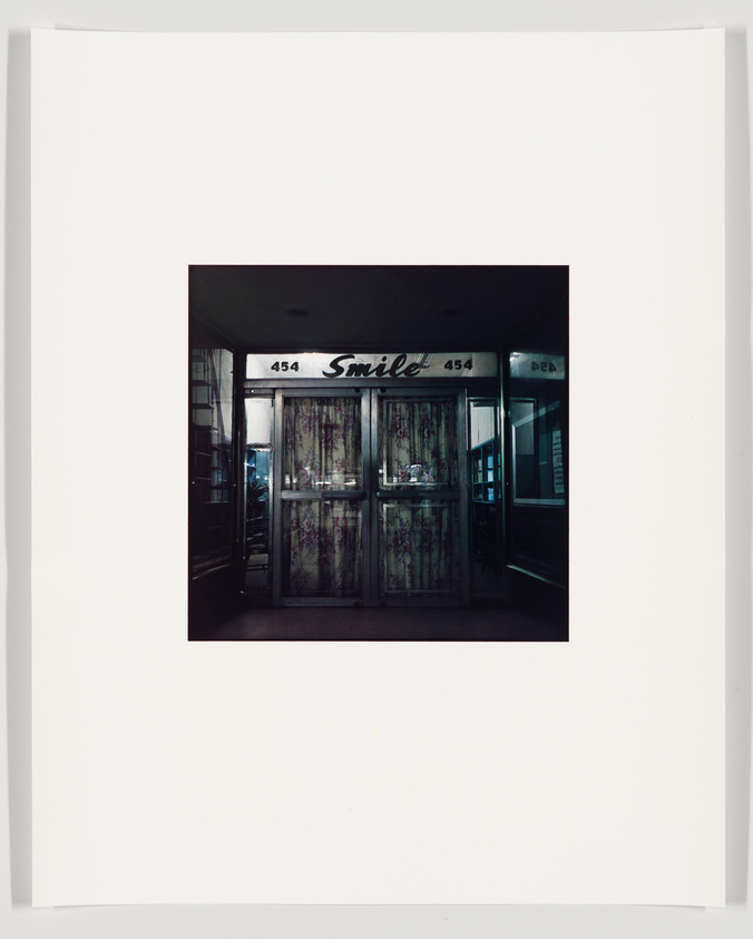 A photograph of a storefront with the word "Smile" written across the top, flanked by the numbers 454. The store's display windows are covered with curtains, and the entrance appears dark and uninviting. The image is centered within a large white border.