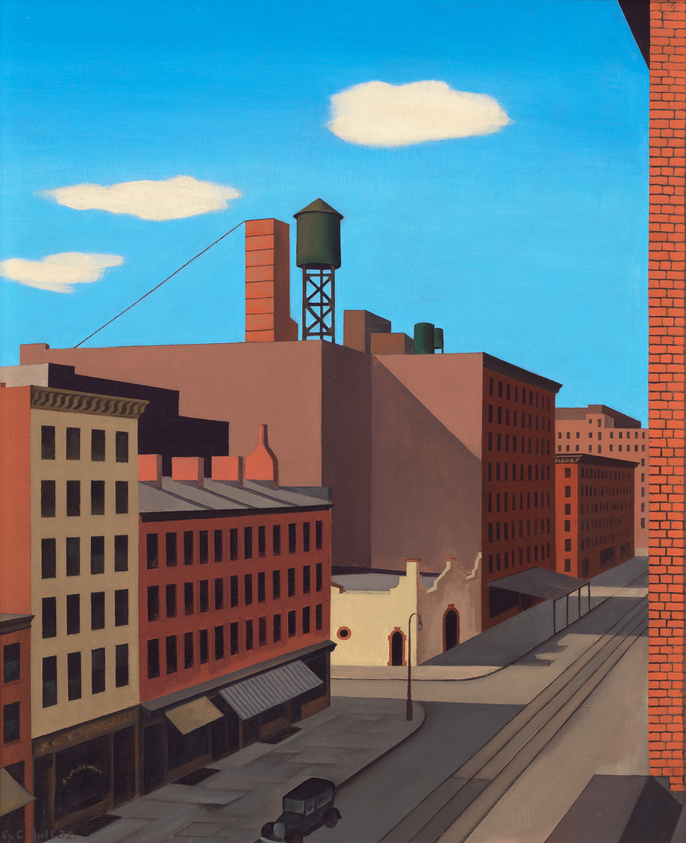 City street with tall brick buildings, a water tower, and a parked car under a clear blue sky.