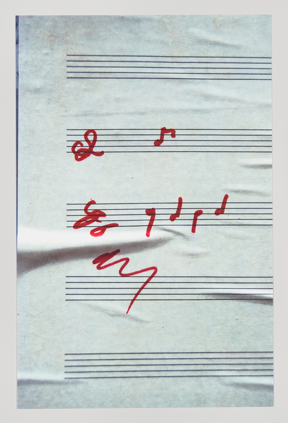 A piece of sheet music with a few red scribbles and musical notes on it, suggesting an incomplete composition or a work in progress.