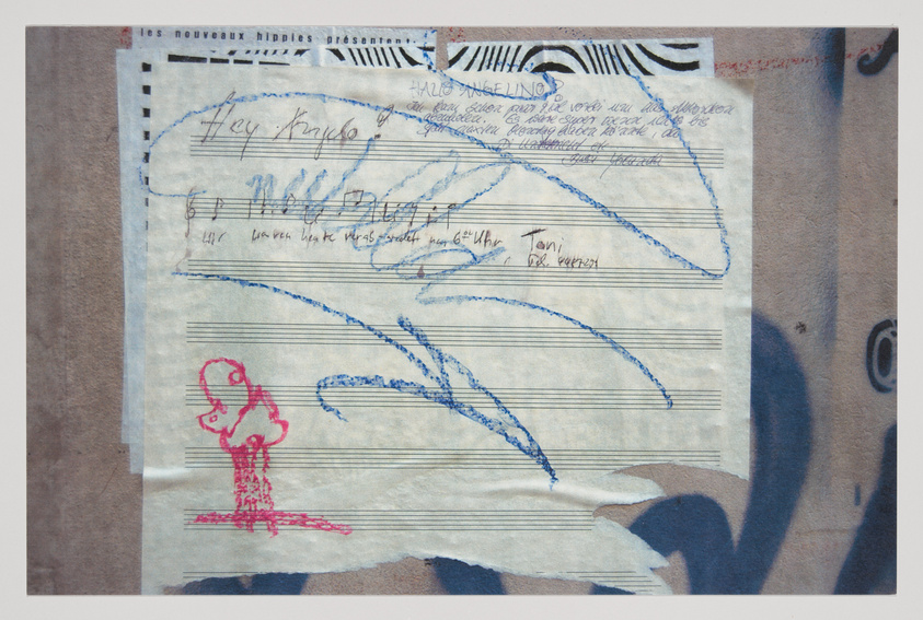 A collage of various papers and textures with handwritten notes, scribbles, and a red drawing of a simplistic figure on lined music sheet paper. The background includes a partial face with an eye, and text that reads "les nouveaux hippies présentent." The overall image has a creative, disorganized aesthetic.