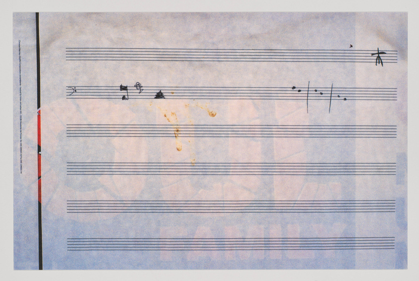 A worn piece of sheet music with a few musical notes and symbols scattered across the staves. There are visible stains and signs of aging on the paper.