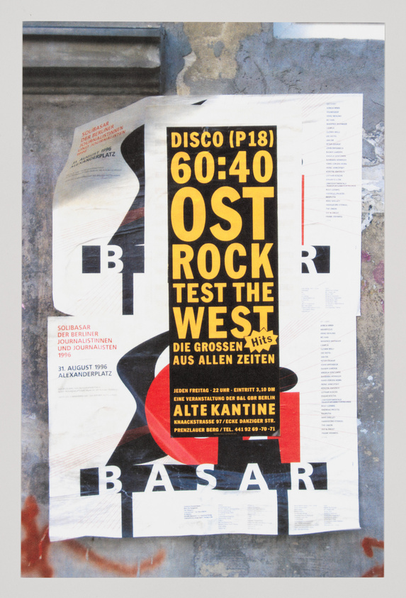 A weathered poster on a wall featuring bold typography advertising a "DISCO (P18) 60:40 OST ROCK TEST THE WEST" event with additional text in German, including dates and location details. The poster has a dynamic layout with a mix of black, white, and yellow text on a red background, partially overlaid by other torn posters.