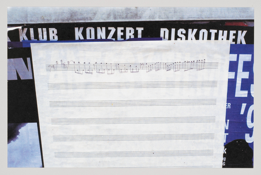 A collage of various elements including a piece of sheet music with a few notes written on it, overlaying parts of posters or flyers with words like "KLUB," "KONZERT," and "DISKOTHEK" in bold letters, suggesting a musical or nightclub theme. The background shows portions of other text and images, creating a layered, textured effect.
