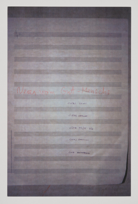 A photograph of a piece of paper with musical staff lines and handwritten text in red that reads "News from Gut - Mensch" at the top, followed by a list of phrases including "Gute Licht," "Guter Geruch," "Gute Taktik WK," "Gutes Gefühl," and "Gute Ernährung." The paper appears aged and is slightly curled at the bottom right corner.