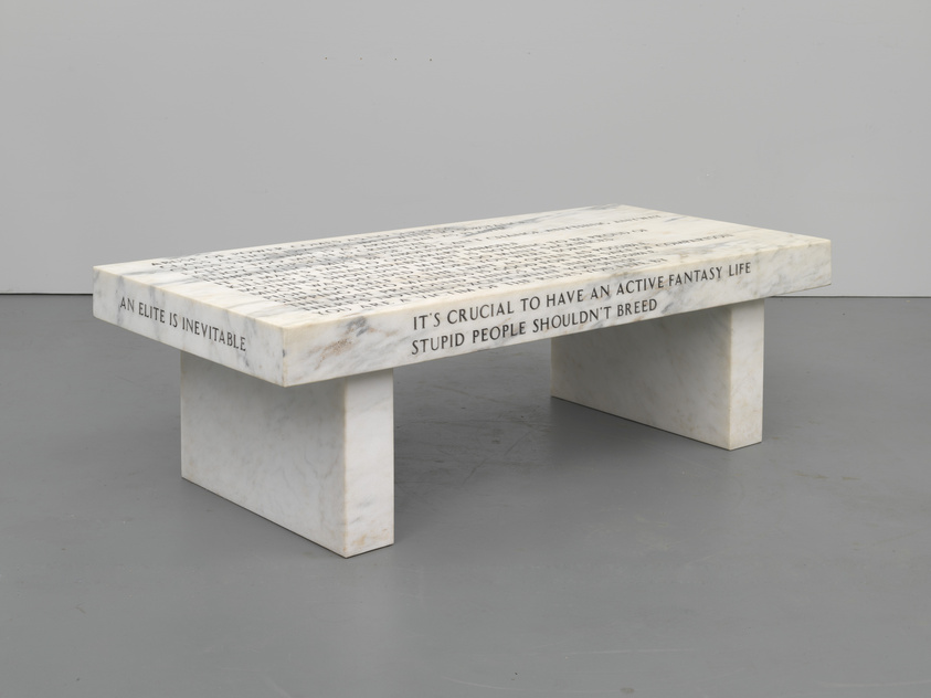 A marble bench with inscriptions on its surface and sides, featuring phrases such as "AN ELITE IS INEVITABLE," "IT'S CRUCIAL TO HAVE AN ACTIVE FANTASY LIFE," and "STUPID PEOPLE SHOULDN'T BREED," set against a plain background.