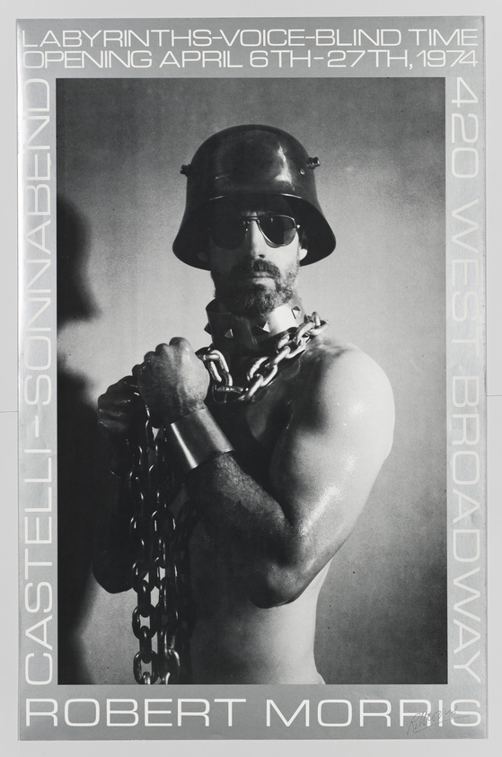 A black and white promotional poster featuring a shirtless man with a muscular build, wearing a helmet, dark sunglasses, and a heavy chain around his neck. Text on the poster reads "LABYRINTHS-VOICE-BLIND TIME OPENING APRIL 6TH-27TH, 1974 420 WEST BROADWAY CASTELLI-SONNABEND" and "ROBERT MORRIS" at the bottom.