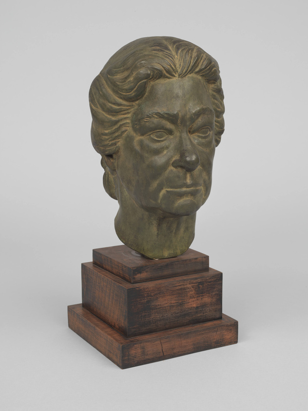 A bronze bust sculpture of a person with detailed hair texture, set on a tiered wooden base, against a neutral background.