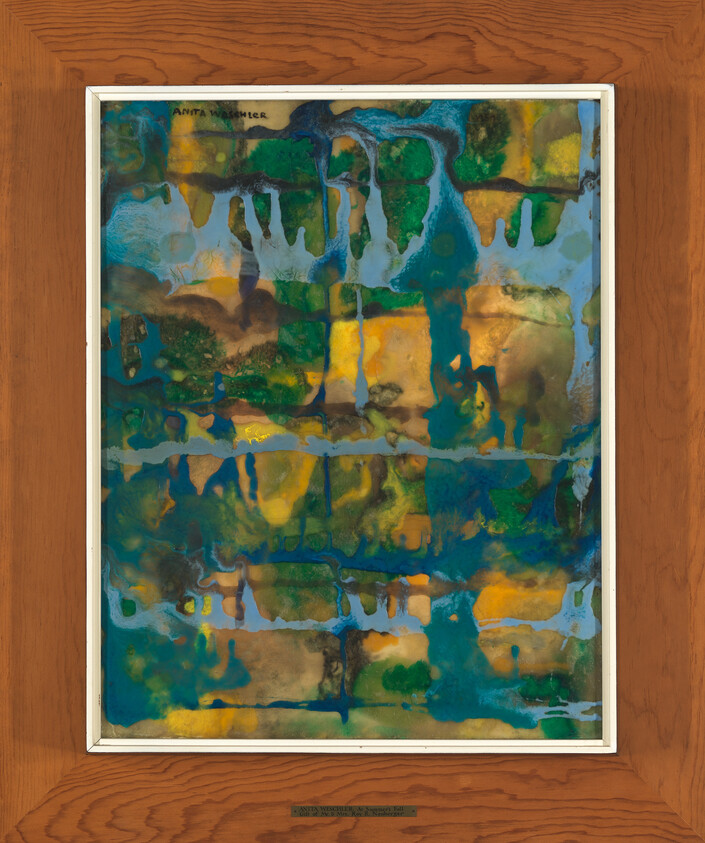 A framed abstract painting with a vibrant blend of blue, green, yellow, and brown hues hangs on a wooden wall. The artwork features a fluid, organic mix of colors that create a marbled or watercolor-like effect. The artist's name, Anita Magsaysay-Ho, is inscribed in the upper left corner of the painting, and a plaque with the artist's name and the title of the piece, "Anito Worshipers," is mounted on the wall below the artwork.