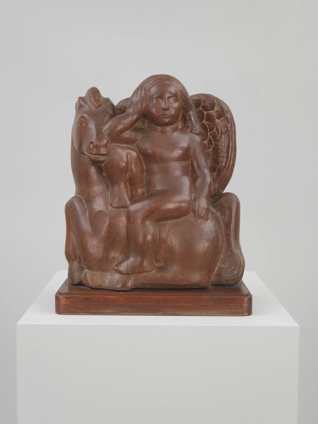 A wooden sculpture depicting a seated figure with a serene expression, flanked by a horse to the left and what appears to be stylized wings or foliage to the right, displayed on a white pedestal against a neutral background.