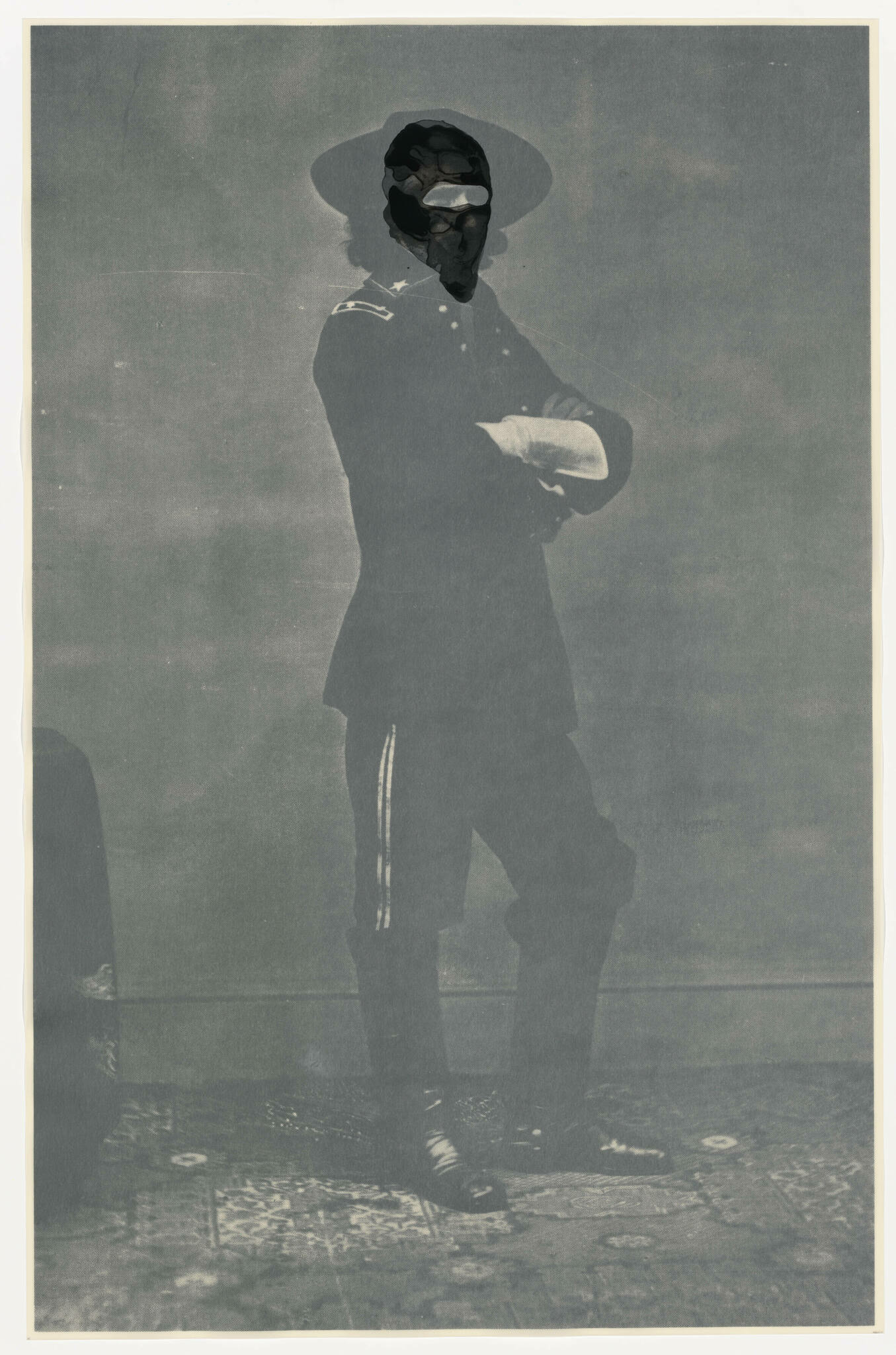 Vintage black and white photo of a person in a military uniform with a wide-brimmed hat, standing with arms crossed. The image is aged with some damage, including a large dark blotch obscuring the face.