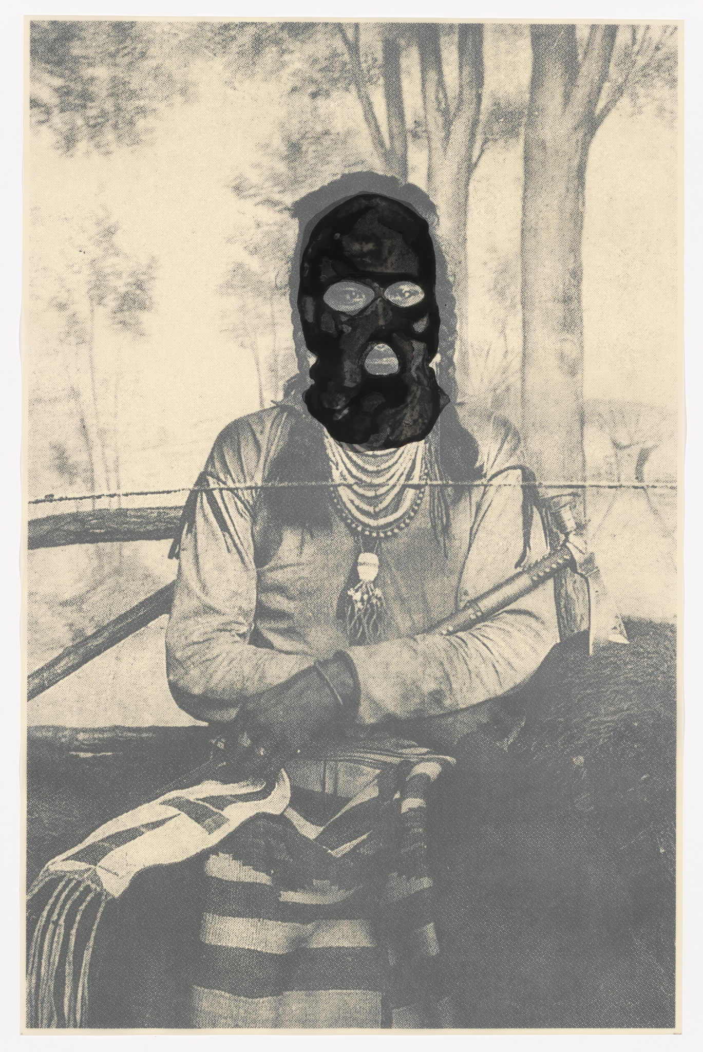Vintage-style photograph of a person wearing a mask with multiple circular openings, sitting in front of a blurred forest background. The individual is dressed in a striped garment with a necklace and holds an object in their right hand. The image has an aged, sepia-toned appearance.