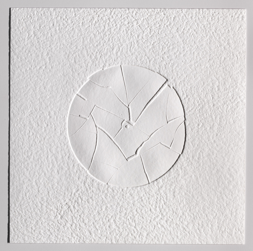 A round shape made of cracked, raised paper pieces sits on a textured white background.