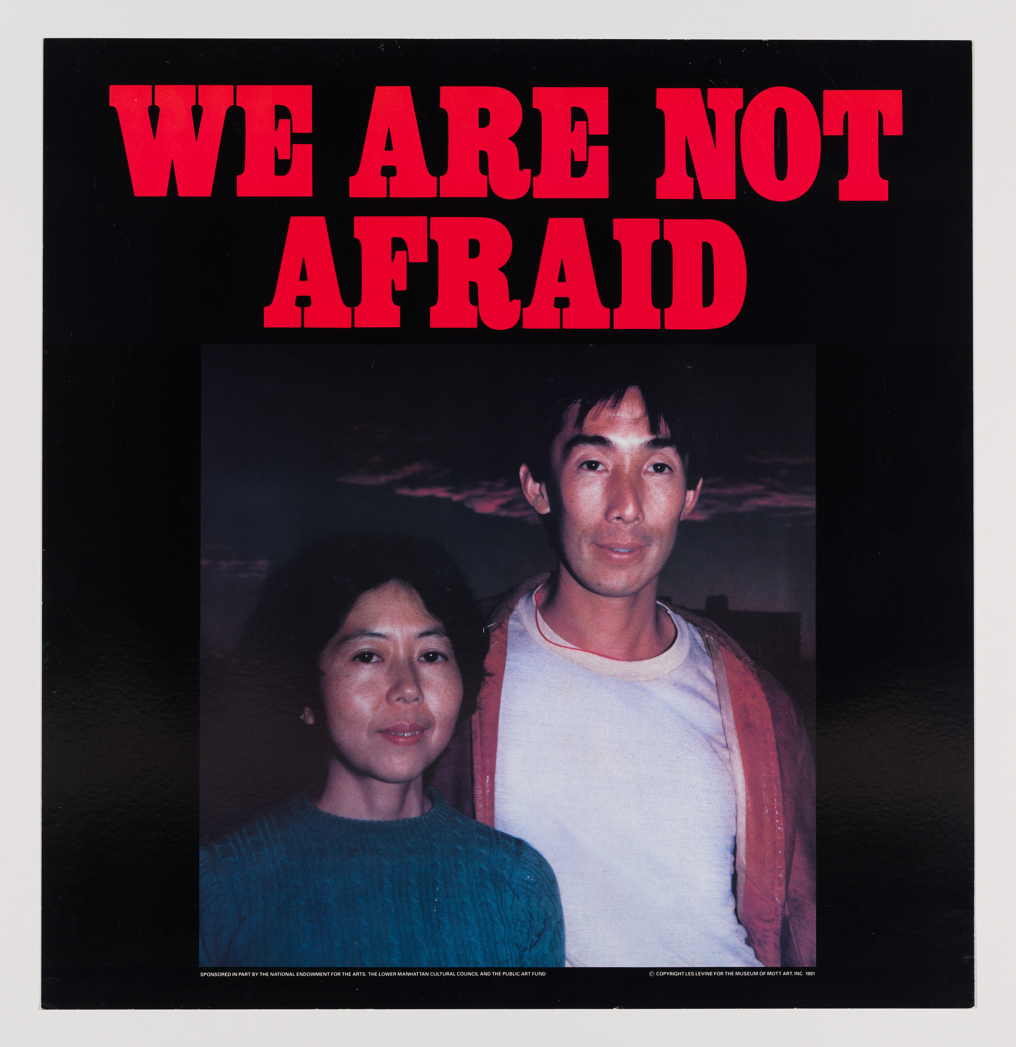 A graphic image featuring a bold red text "WE ARE NOT AFRAID" at the top against a black background. Below the text is a photograph of a man and a woman standing side by side. The woman is wearing a blue sweater, and the man is in a white shirt with a red vest. The bottom of the image includes a credit line that reads "Sponsored in part by the National Endowment for the Arts," among other text.