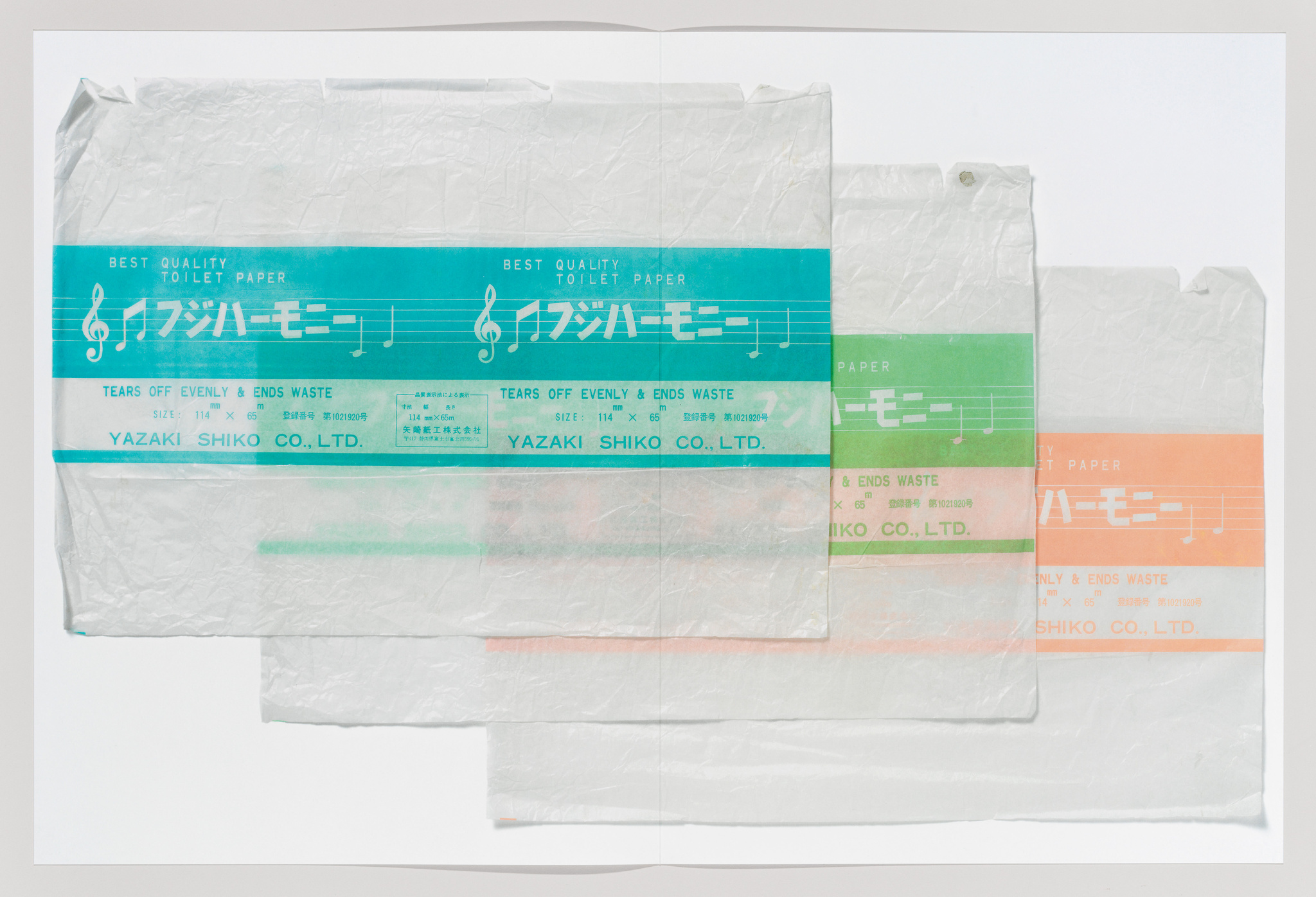 A collection of translucent toilet paper sheets with printed text and musical notes in different colors, including blue, green, and orange, with the text "BEST QUALITY TOILET PAPER" and "YAZAKI SHIKO CO., LTD." visible.