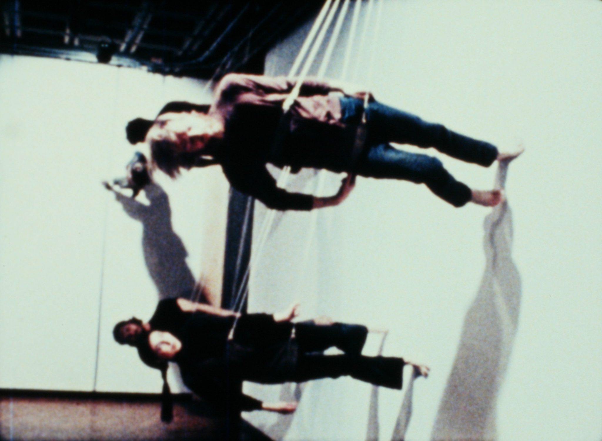 People suspended horizontally with ropes, creating an illusion of walking on a vertical surface.