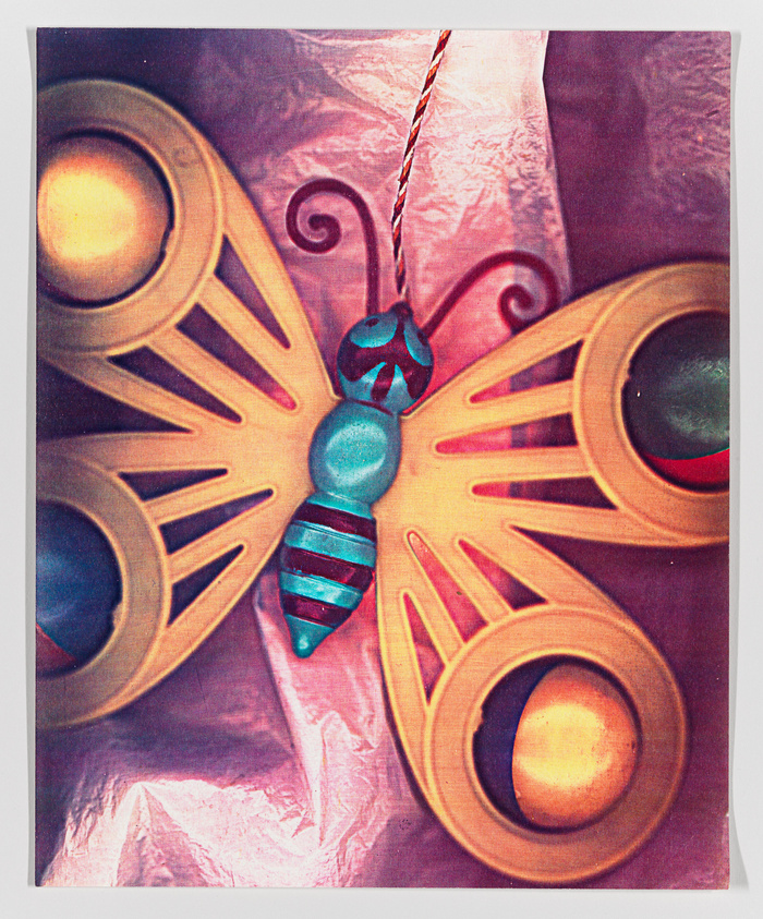 Colorful butterfly kite with intricate patterns against a shiny pink background.