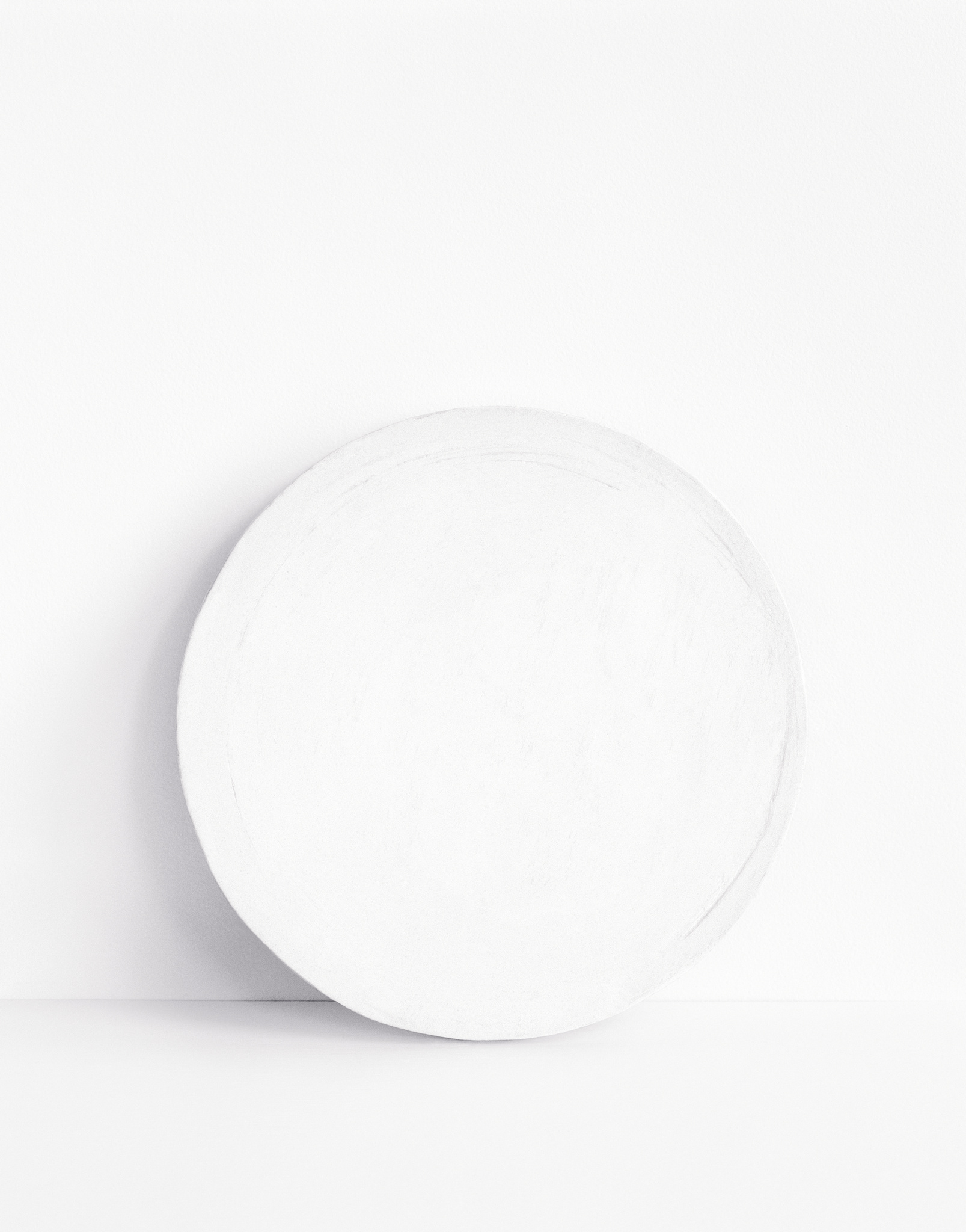 A plain white circular object with a textured surface, possibly a ceramic plate, displayed against a white background with soft shadows.