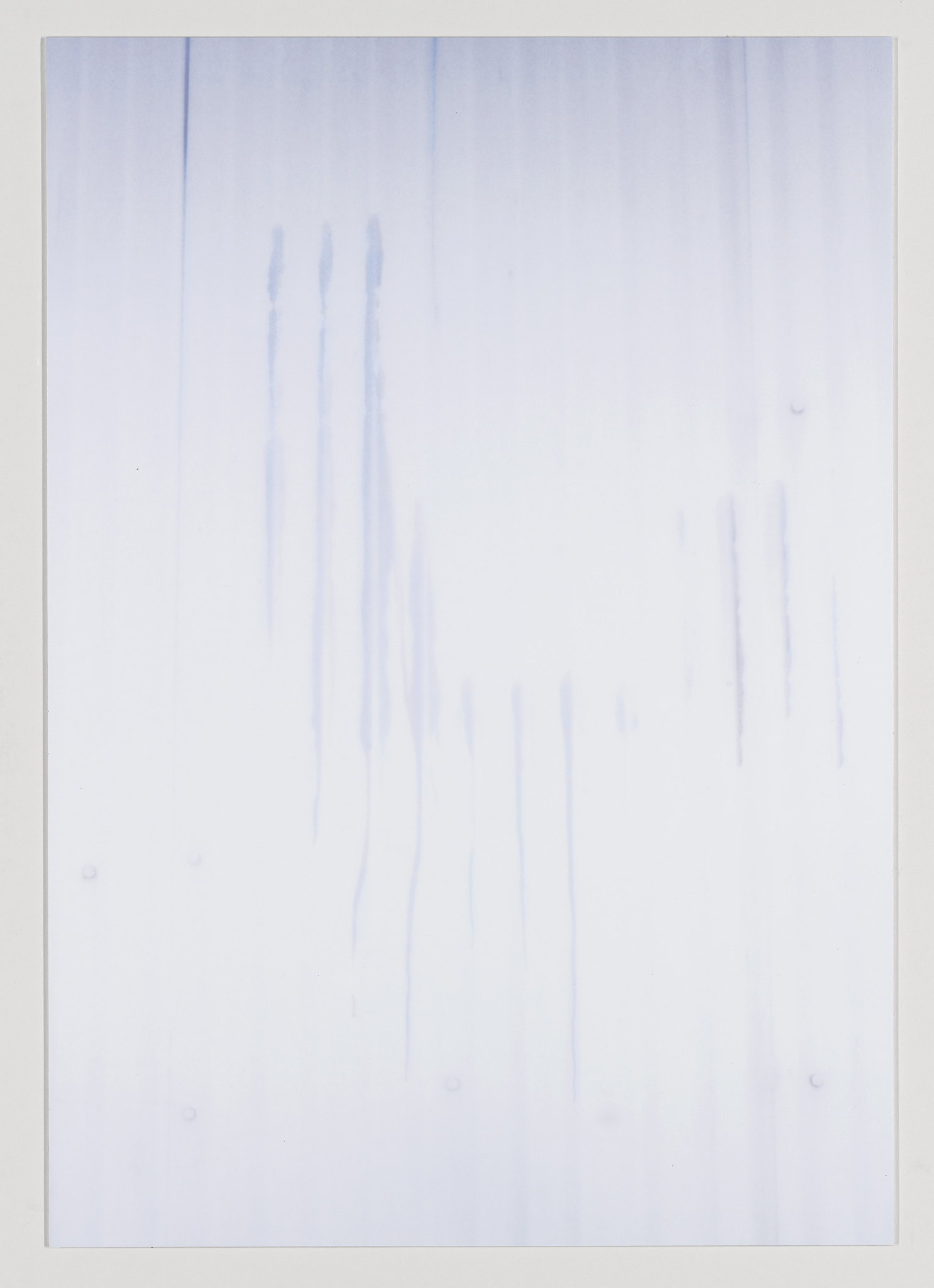 A vertical image showing a white background with subtle vertical streaks of blue dye or ink running down the surface, creating a soft, watercolor-like effect. The overall appearance is minimalist and abstract.
