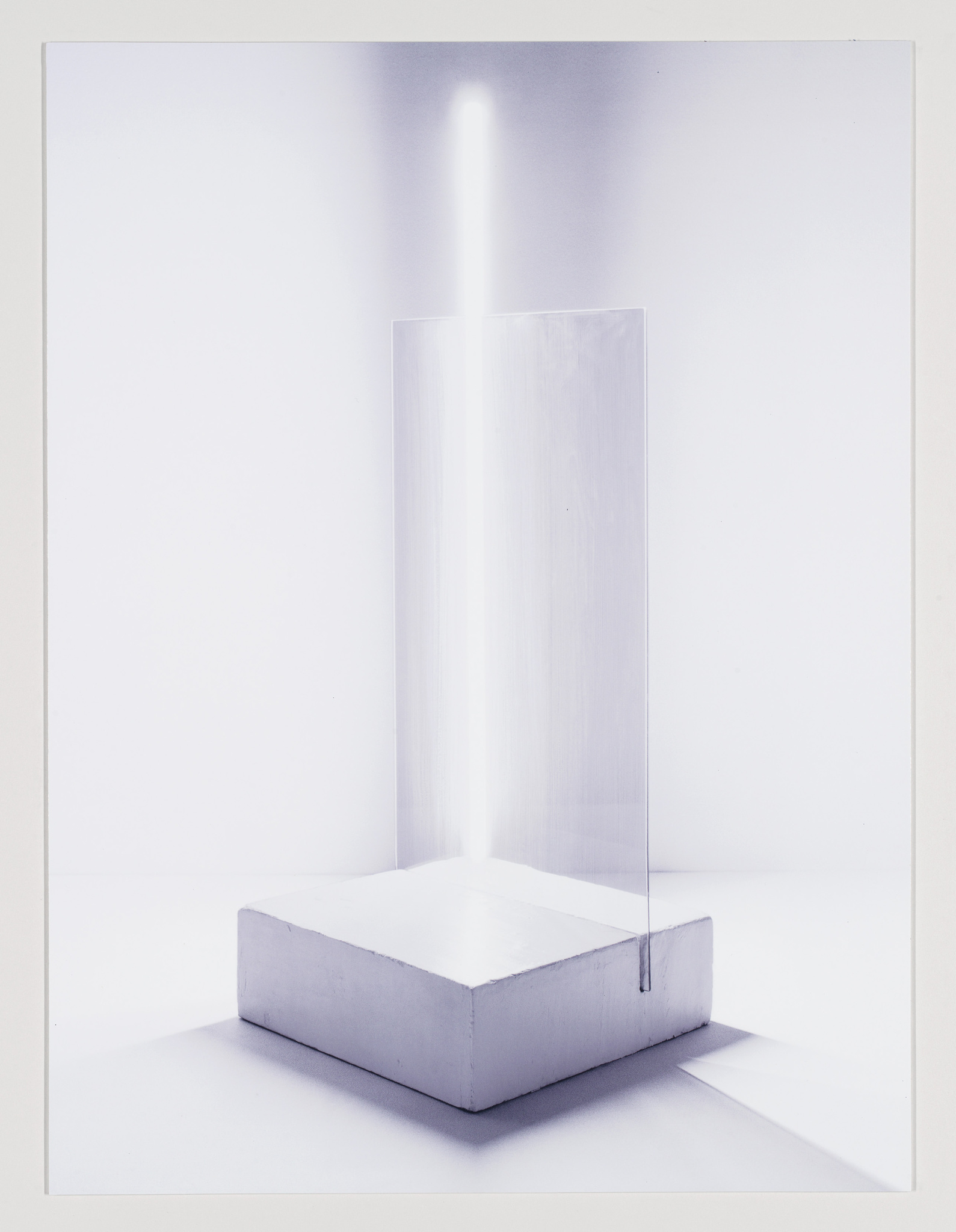 A minimalist art installation featuring a vertical, translucent rectangular prism on a white pedestal, with a bright light source shining through the top, creating a luminous line effect against a white background.