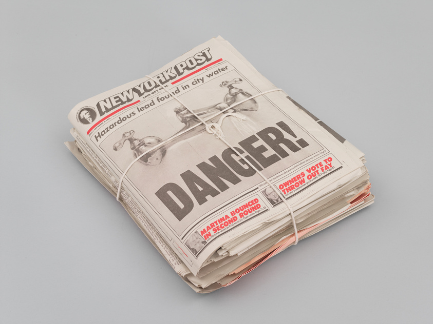 A bundle of New York Post newspapers tied with twine, featuring a headline about hazardous lead with the word "DANGER" in large print.