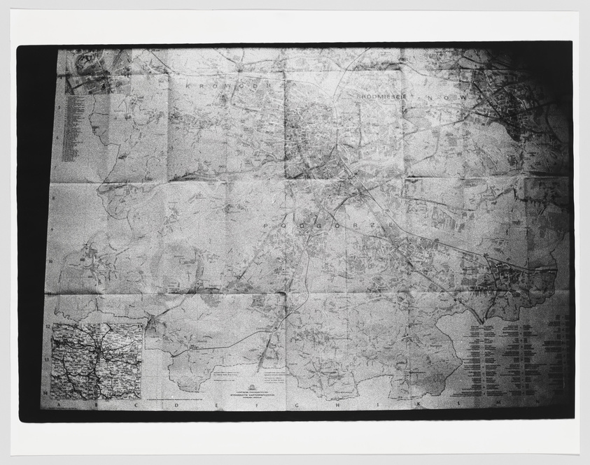 A black and white photo of a worn and creased map with various sections, some text, and grid lines visible, suggesting it's a navigational or topographical map. The map is not fully legible due to the wear and the monochrome reproduction.