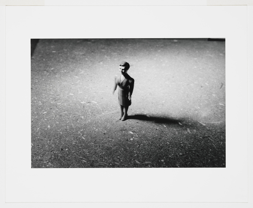 A solitary figure stands in a vast, shadowy space, evoking a sense of introspection or isolation.