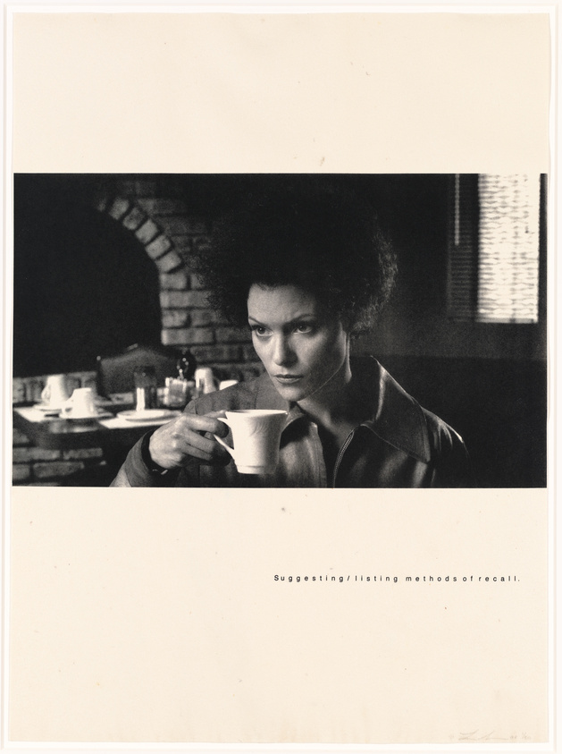 A black and white photo of a woman with an afro hairstyle sitting at a table, holding a white cup, with a pensive expression on her face. The setting appears to be a diner with a brick wall in the background and a window with blinds to the right. Below the image, there is text that reads "Suggesting/listing methods of recall."